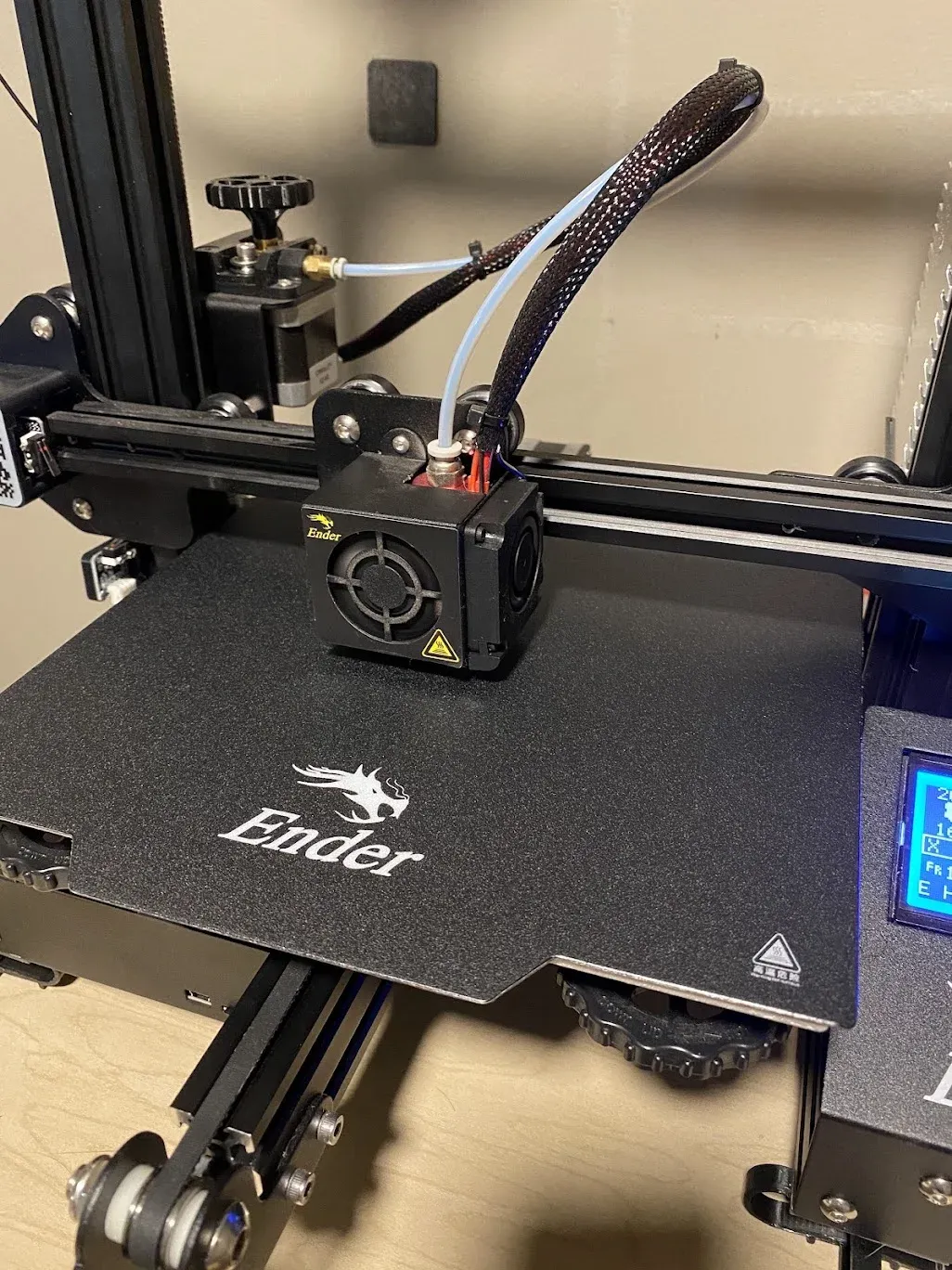 Close-up of an Ender 3 print head over its black textured print bed